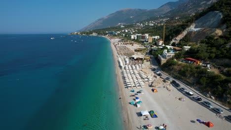 Beautiful-Bay-of-the-Ionian-Sea-with-Turquoise-Waters-and-White-Sand-Beach-Filled-with-Sun-Umbrellas-in-Dhermi