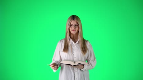 Mujer-Joven-Rubia-Concentrada-Escribiendo-Notas-En-Un-Bloc-De-Notas-Sobre-Fondo-Verde,-Fotografía-De-Estudio