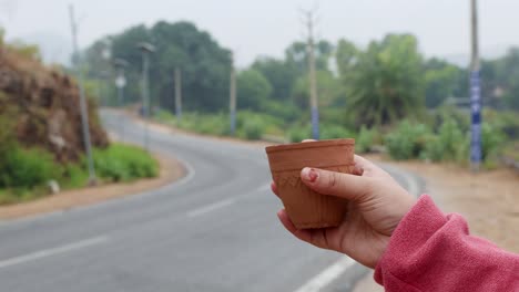 girl-enjoying-hot-tea-served-in-traditional-pottery-clay-cup-with-blurred-highway-landscape