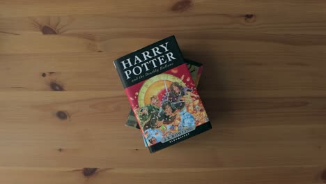 Hände-Stapeln-Harry-Potter-Bücher-In-Verschiedenen-Sprachen-übereinander-Auf-Einem-Holztisch