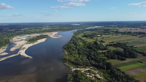 Vista-Aérea-Del-Río-Vístula,-Una-Ribera-Natural-Y-Salvaje-Rodeada-De-Campos-Verdes,-Con-Un-Cielo-Azul-En-Un-Día-De-Verano.