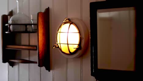 Old-lamp-and-a-shelf-hanging-on-a-wodden-wall-in-a-cabin-on-a-traditional-sailing-ship