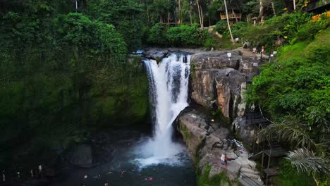 Vista-Aérea-Que-Muestra-La-Impresionante-Cascada-De-Tegenungan-En-Bali,-Indonesia,-Capturando-El-Exuberante-Entorno-Y-A-Los-Turistas-Disfrutando-De-Las-Refrescantes-Aguas.