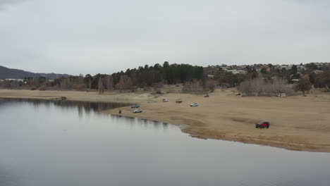 Toma-Aérea-De-Vehículos-4x4-Estacionados-En-La-Orilla-Del-Lago-Jindabyne,-Australia