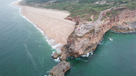 Luftaufnahme-Im-Orbit-über-Den-Wunderschönen-Leuchtturm-Von-Nazare-Und-Den-Wunderschönen-Strand-In-Der-Gegend