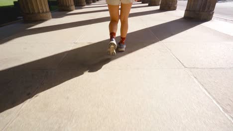 Asian-woman-walks-thoughtfully-through-the-towering-columns-of-a-classical-architectural-site-in-Berlin,-absorbing-the-historical-ambiance-at-Museum-Island-Germany