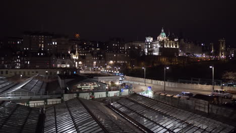 Panning-shot-of-Edinburgh-at-night-with-North-Bridge,-Edinburgh-Royal-hotel,-Waverley-railway-station-and-Edinburgh-castle