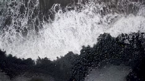 Cinematic-top-down-drone-aerial-of-rhythmic-waves-crashing-on-the-black-volcanic-sand-of-Maui-beaches,-Hawaii