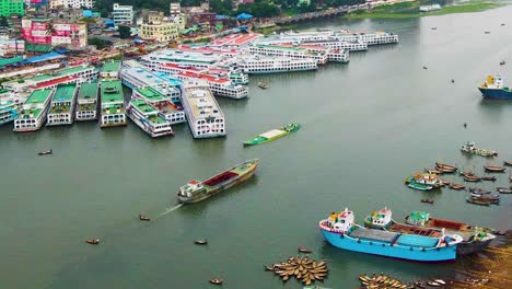 Colorful-boats-and-ferries-on-a-river-near-an-urban-area,-aerial-shot