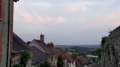 Toma-Panorámica-Lenta-De-Gold-Hill-Al-Atardecer,-Antigua-Calle-Adoquinada-Inglesa,-Shaftesbury,-Dorset,-Reino-Unido,-4k