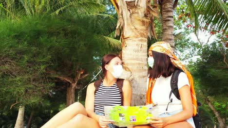 Tourist-girls-wearing-protective-masks-fearing-infection-of-Covid19-or-Coronavirus-on-Asian-tropical-beach-in-Thailand