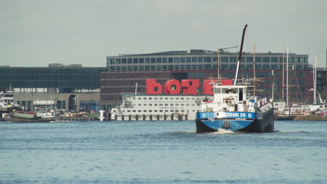 Ferry-Boat-At-IJ-River-With-Amstel-Botel-In-Background-In-Amsterdam,-Netherlands