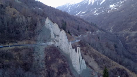 Car-driving-through-Euseigne-pyramids,-Switzerland.-Aerial-circling