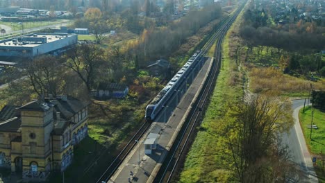 Personenzug---Vorbeifahrender-Bahnhof---Luftaufnahme