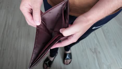 The-man-checks-his-brown-wallet-which-has-no-money-in-it