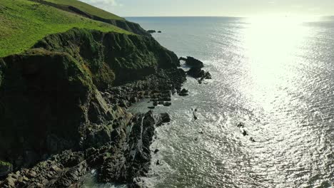 Vista-Aérea-De-Escarpados-Acantilados-Marinos-Con-Las-Olas-Rompiendo-Suavemente-En-La-Base-En-Un-Soleado-Día-De-Verano-En-El-Sur-De-Irlanda