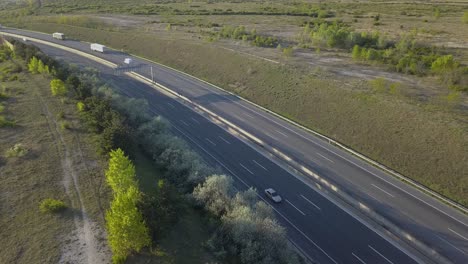 Cars-and-trucks-driving-on-asphalt-highway-slight-curve,-still-aerial-shot