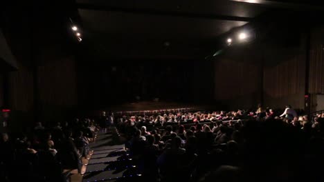 Entrar-Por-La-Puerta-De-Un-Teatro-O-Cine-Con-Todos-Los-Asientos-Llenos-De-Gente.