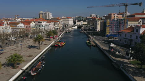 Aerial-shot-along-waterway-canal-downtown-on-sunny-day,-Aveiro