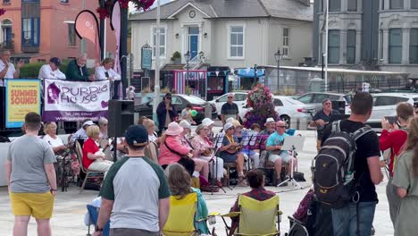 Group-of-senior-people-playing-musical-instruments-and-singing-in-front-of-a-crowd-at-Bray