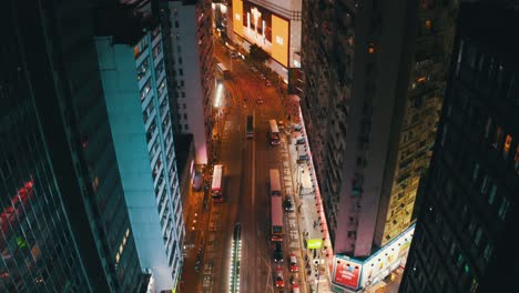 Drohnenaufnahme,-Die-Nachts-Vorwärts-Fährt-Und-Mitten-In-Der-Stadt-Hongkong-An-Der-Kreuzung-Causway-Bay-Nach-Oben-Schwenkt