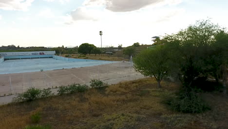 Wide-rotating-drone-shot-of-abandoned-waterpark-headed-towards-wave-pool,-at-Breakers-in-Tucson-Arizona