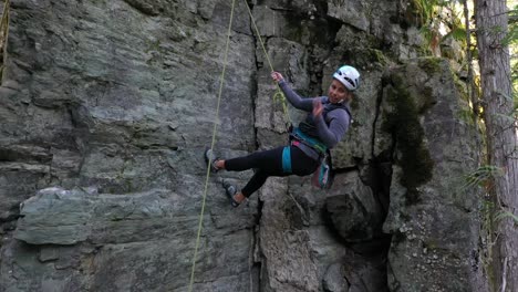 Escaladora-Con-Arnés-De-Seguridad-Y-Casco-Descendiendo-Por-Un-Acantilado-Rocoso-En-Whitefish,-Montana