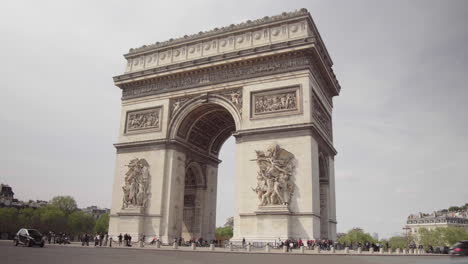 Tráfico-Frente-Al-Arco-Del-Triunfo-A-La-Luz-Del-Día-En-Abril,-París,-Francia,-Toma-Panorámica-De-4K,-Nublado