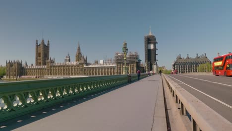 Westminster-bridge-overlooking-the-Big-Ben-tower-during-covid-quarantine,-red-buses-and-few-people