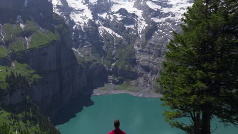 Hombre-Volando-Sobre-Las-Montañas-Sobre-El-Lago-Oeschinen-En-El-Oberland-Bernés,-Suiza