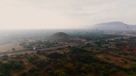 Panoramablick-Auf-Die-Sonnenpyramide-Im-Morgennebel-Und-Heißluftballons,-Die-Rechts-Fliegen