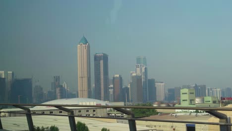 Bewegte-Aufnahme-Von-Wolkenkratzern-Und-Firmengebäuden-Aus-Dem-U-Bahn-Fenster-In-Der-Innenstadt-Von-Dubai,-Vereinigte-Arabische-Emirate