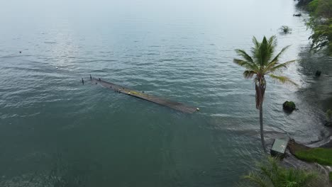 Aerial-orbiting-shot-of-a-wooden-dock-under-the-tide-at-Lake-Victoria