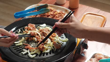 Pareja-Joven-Cocinando-Rodajas-De-Carne-De-Res-Junto-Con-Cebolla-Usando-Palillos