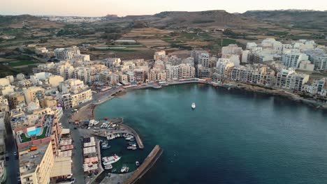 360-Grad-Luftaufnahmen-Zeigen-Den-Hafen-Von-Marsalforn,-Gebäude-Und-Die-Strandpromenade-Während-Der-Goldenen-Stunde-Bei-Sonnenuntergang-Auf-Gozo,-Malta