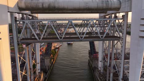 Cargo-ship-seen-through-open-railway-bridge-in-Netherlands,-aerial-rise