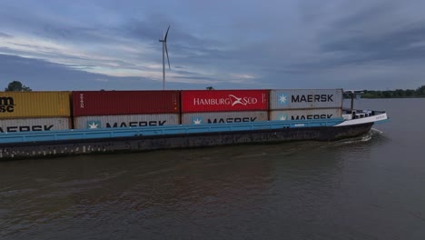 Container-ship-transporting-cargo-on-a-river-under-a-cloudy-sky