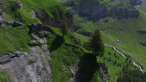 Male-Tourist-Standing-On-The-Cliff-In-Oeschinen-Lake,-Bernese-Oberland,-Switzerland---Aerial-Drone-Shot