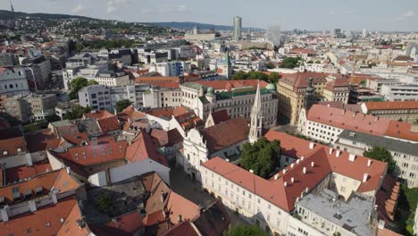 Los-Edificios-Con-Tejados-Rojos-De-Bratislava-Con-La-Iglesia-De-La-Anunciación-En-Un-Día-Soleado,-Vista-Aérea