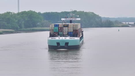 Commercial-vessel-sailing-down-a-river-with-containers