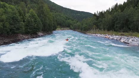 Aerial-view-of-a-kayaker-navigating-white-water-rapids-through-a-picturesque-river-surrounded-by-lush-greenery-and-mountains