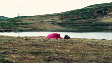 Una-Tienda-De-Campaña-Roja-Se-Instaló-En-La-Orilla-Del-Lago-Interior-Kjøåkertjønna-En-Osen,-Condado-De-Trøndelag,-Noruega---Fotografía-De-Un-Dron-En-órbita