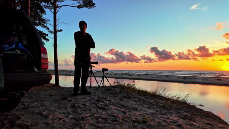 Silhouette-Einer-Person-Mit-Kameraausrüstung-Bei-Sonnenuntergang-Am-Strand