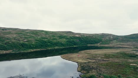 Two-lakes,-Including-Inner-Kjøåkertjønna,-are-Nestled-in-a-Valley-Surrounded-by-a-Mountainous-Landscape-in-Osen,-Trøndelag,-Norway---Aerial-Pullback-Shot