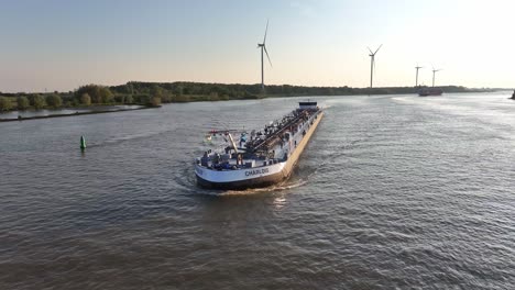 El-Buque-De-Carga-Charlois-Navega-Por-El-Río-Barendrecht-Bajo-Un-Cielo-Despejado-Con-Turbinas-Eólicas-Al-Fondo