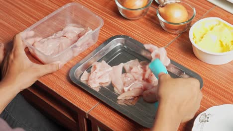 Young-Man-Preparing-Chicken-Fillet-On-Tray-For-Making-Chicken-Steak