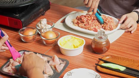 Hombre-Y-Mujer-Asiáticos-Marinando-Carne-De-Pollo-Y-Rodajas-De-Carne-Con-Especias-Para-Hacer-Una-Barbacoa-Al-Estilo-Coreano