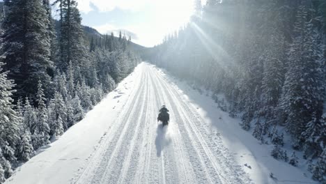 Drohne-Folgt-Einem-Schneemobil-An-Einem-Sonnigen-Tag-Im-Wald