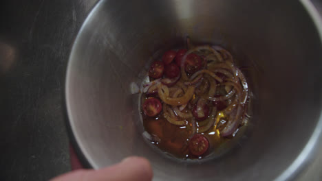 Beautiful-slow-motion-shot-of-a-bowl-of-onions,-cherry-tomatoes-and-octopus-chunks-while-the-chef-is-pouring-oil-into-it