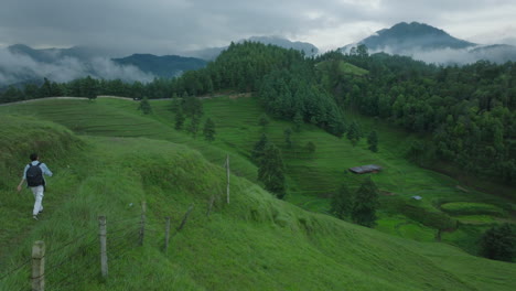 A-drone-shot-of-male-tourist-in-Nepal,-explores-the-lush-greenery-of-the-valley-while-hiking-in-the-hills-of-Makwanpur